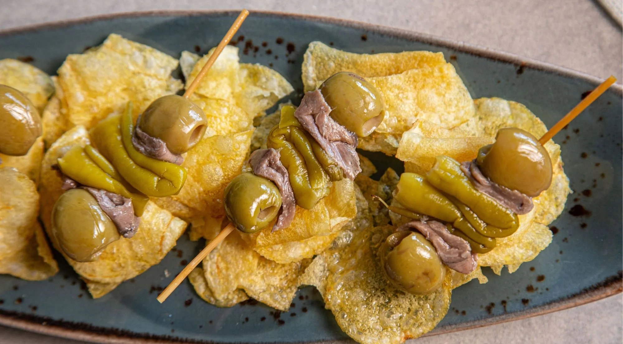 Gilda skewers of olive, anchovy and guindilla pepper served over crisps