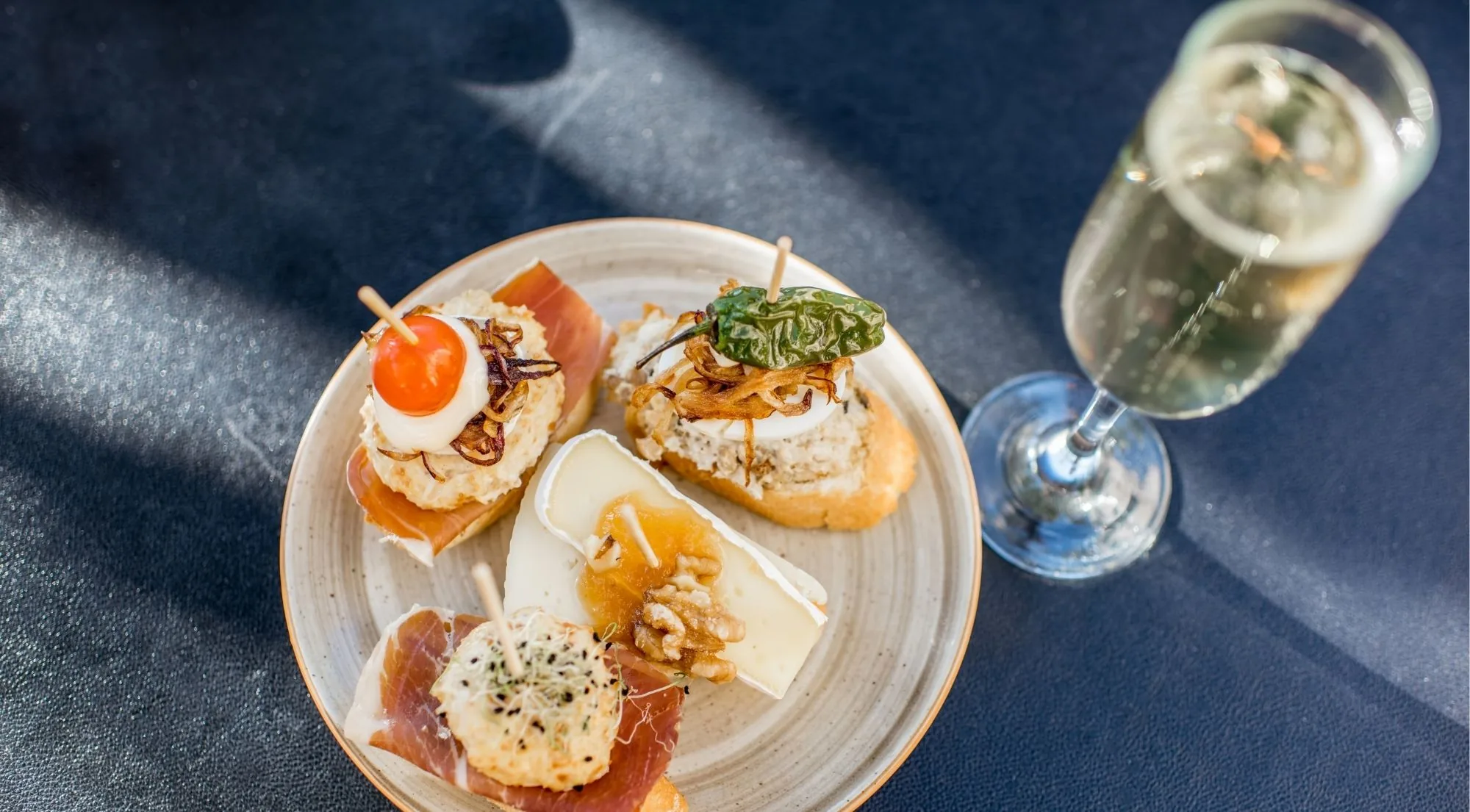 Plate of pintxos with a glass of txakoli poured in the Basque style