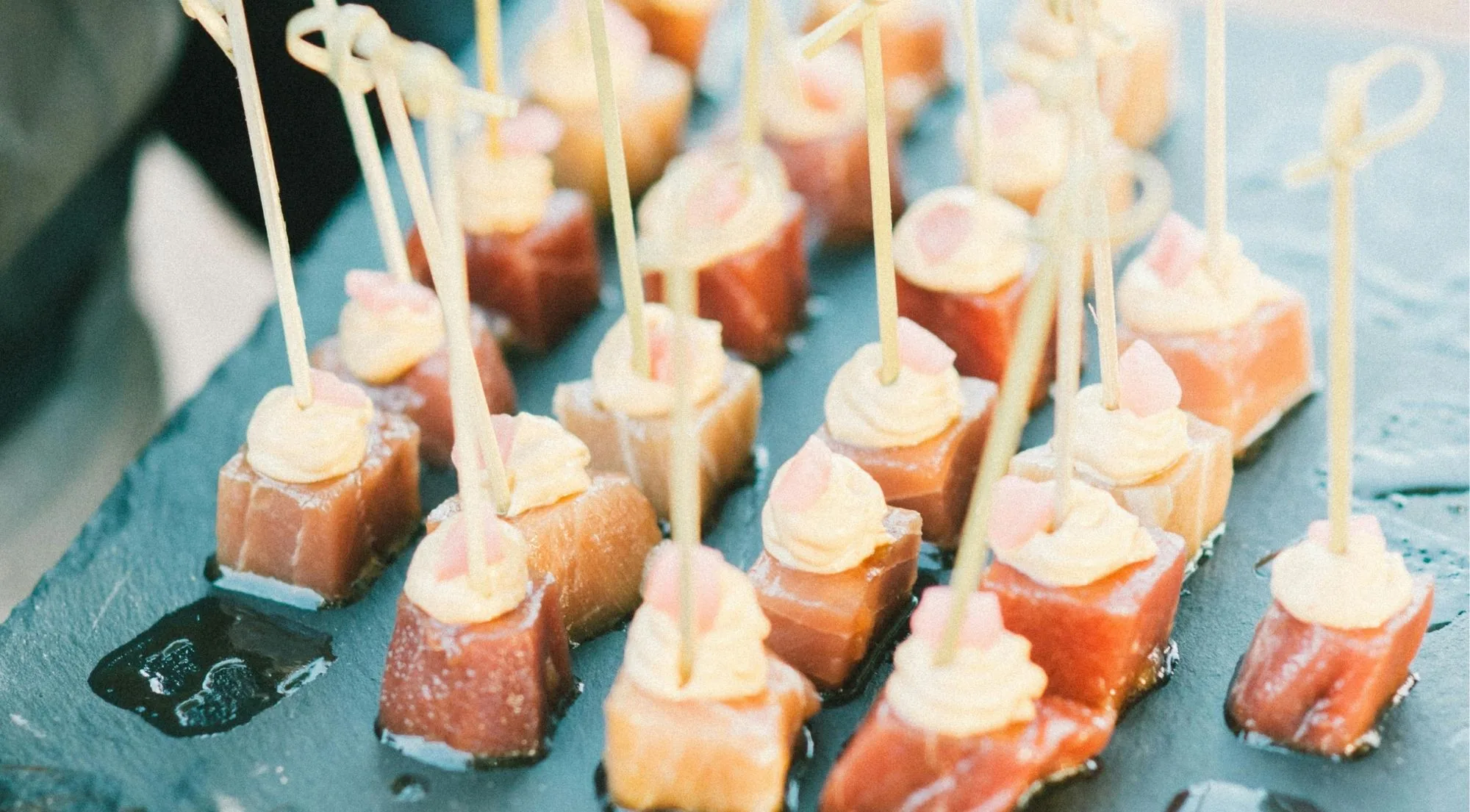 Cured tuna pintxos topped with piped pepper mousse on a slate tray