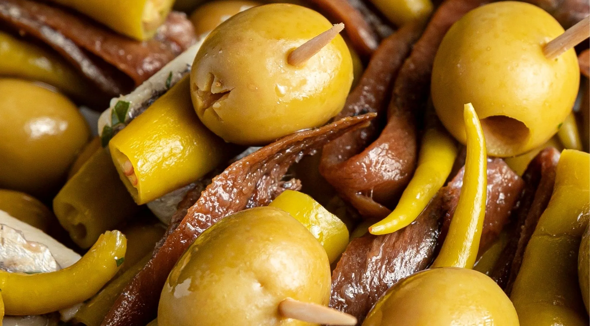 Close-up of green olives, anchovy fillets and guindilla peppers on cocktail sticks