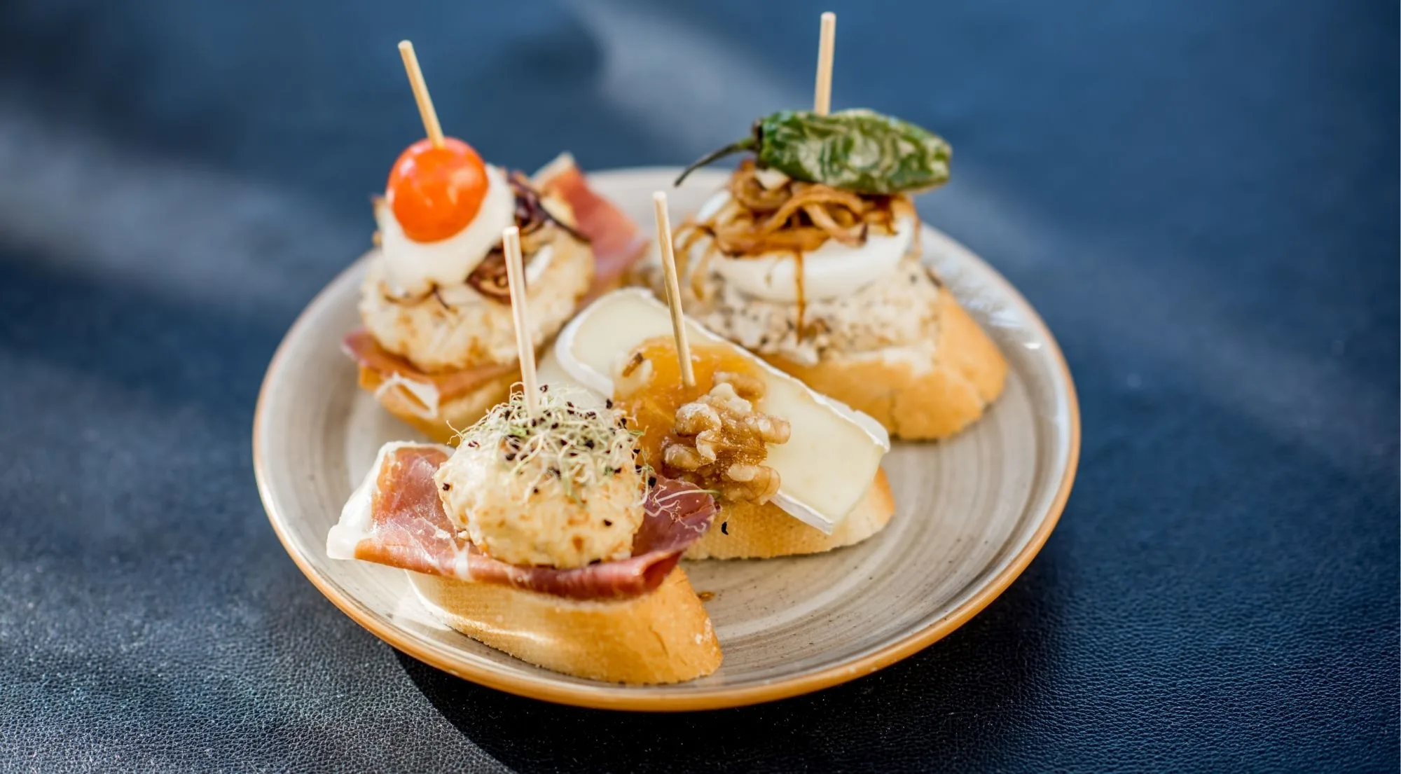 Plate of pintxos with brie, walnut, jamon and a quail-egg tartlet