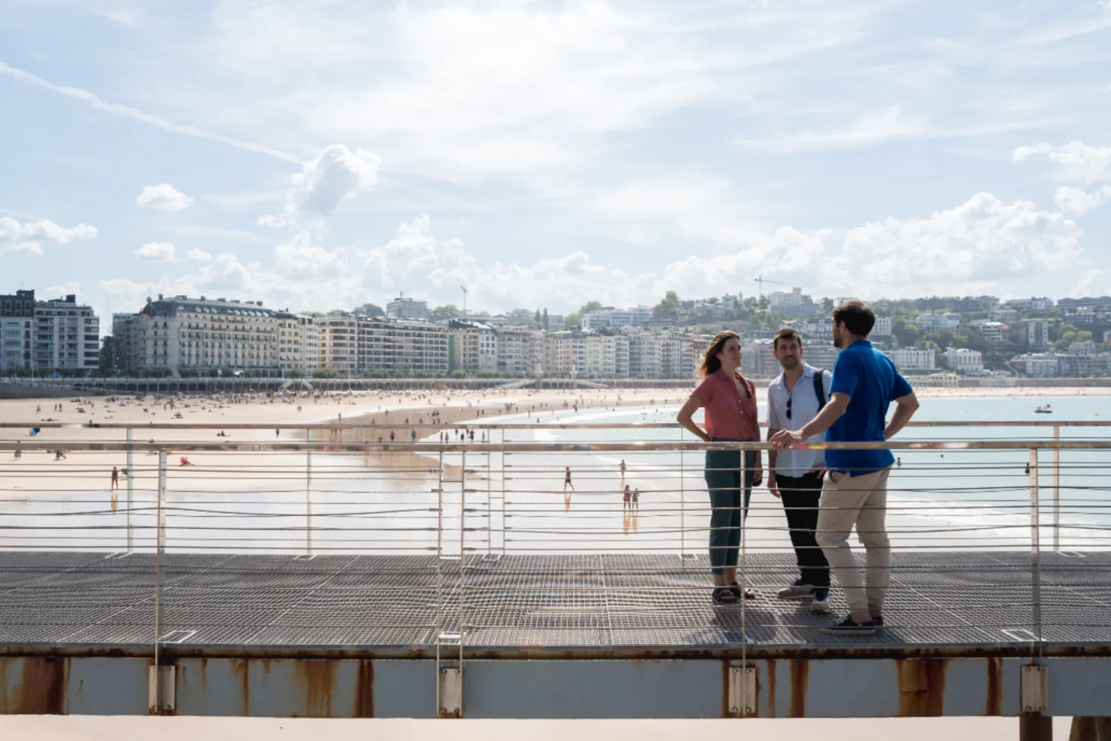Three guests on the Kursaal bridge deck looking back along the Zurriola beachfront