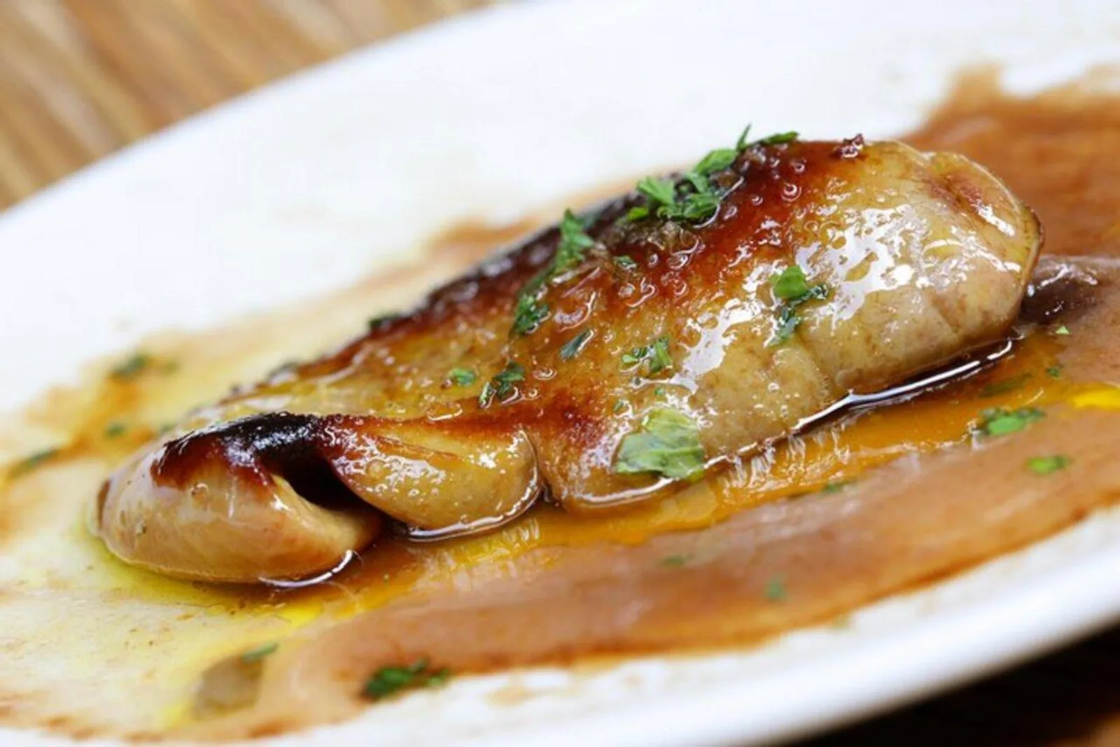 Seared foie gras pintxo glazed in sauce and served on a white plate