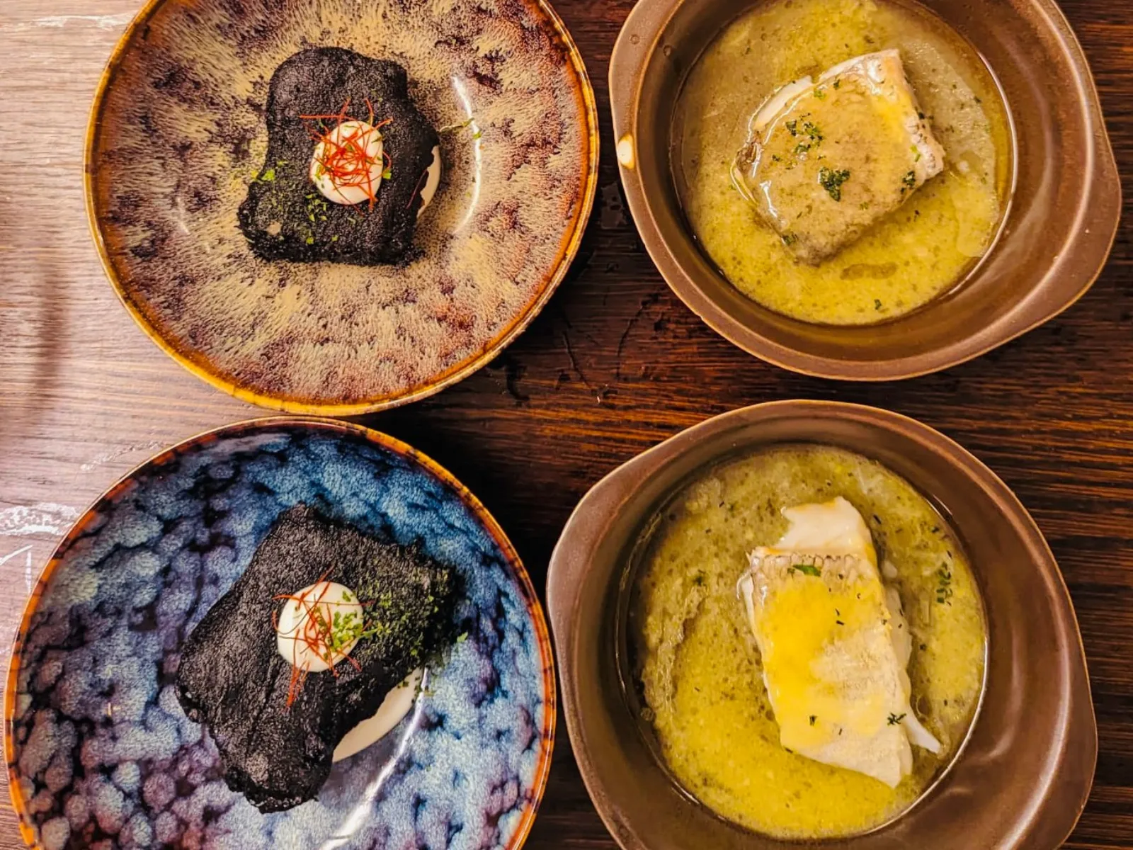 Four Basque dishes shot from above: seared foie, cod in pil-pil sauce and cured tuna