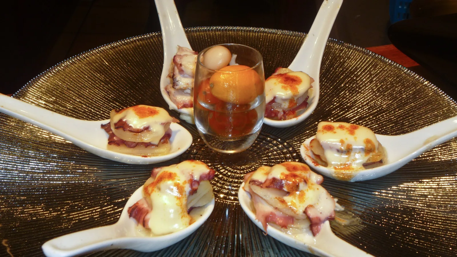 Tasting spoons of Iberian ham and quail egg arranged in a circle on a gold platter