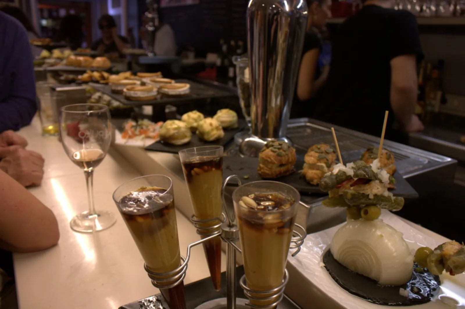Bar counter loaded with pintxos and layered dessert glasses in the Old Town