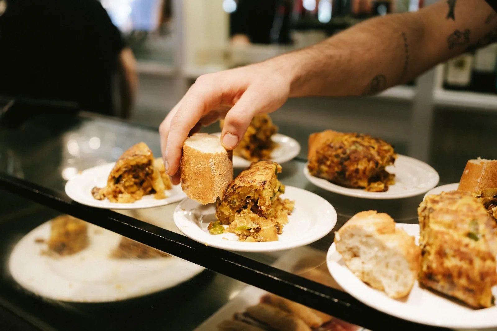 Bar hand reaching across a counter of tortilla and Basque cheesecake slices