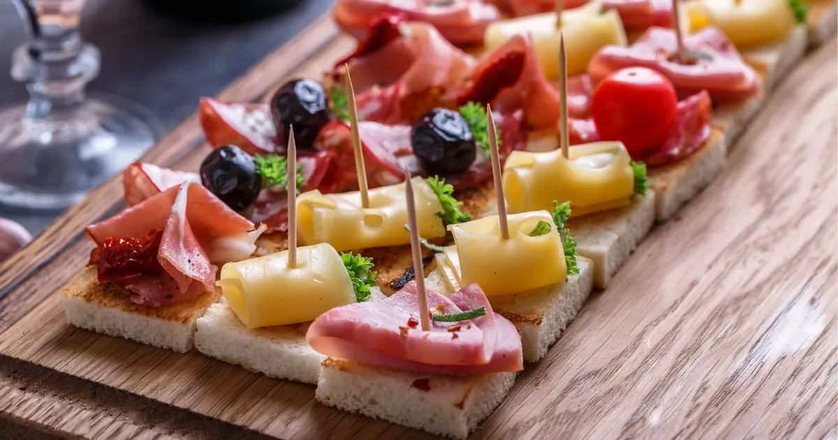 A board of pintxos with ham, cheese and olives on a San Sebastián bar counter